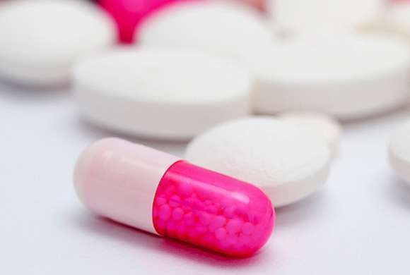 Comprimidos brancos e uma cápsula metade rosa e metade pink 