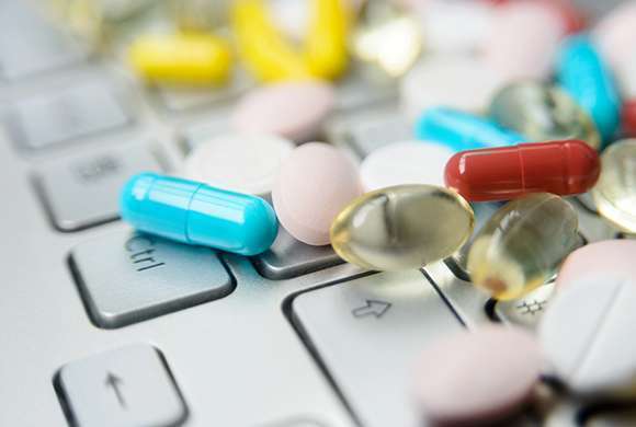 Capsulas de medicamentos soltas sobre um teclado de computador