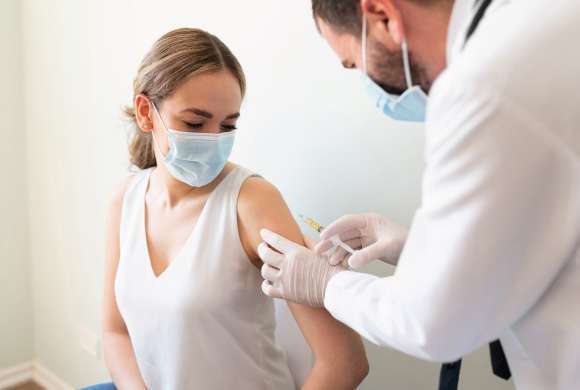 Profissional de saúde aplica vacina em paciente