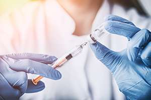 Profissional da saúde com luva aplica vacina em paciente
