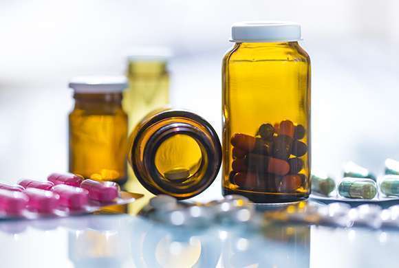 Imagem mostra cartelas e vidros de medicamentos sobre uma mesa.