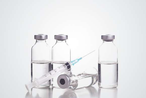 Ampolas de vacina ao lado de uma agulha com seringa.