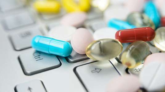Imagem de um teclado de computador coberto de cápsulas de medicamentos