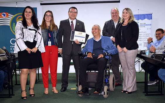 Dr. Marcos Machado segura o selo de acessibilidade rodeado por outros diretores do CRF-SP e pelo secretário Cid Torquato