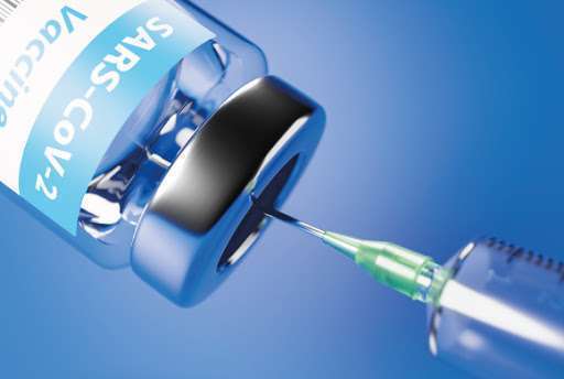 Um frasco de vacina escrito Sars-Cov2 de lado e uma seringa sugando o líquido. Fundo azul claro.
